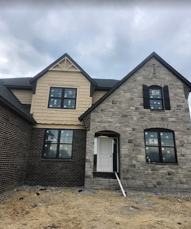 New home exterior with shake siding, masonry, and black windows